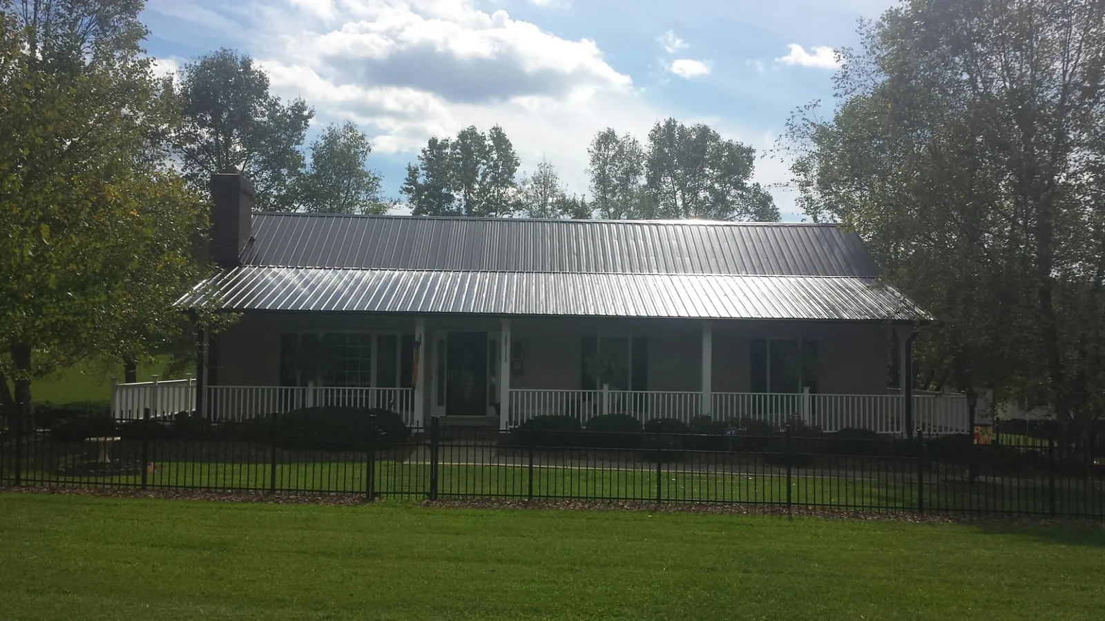 Gray metal roof on a brick ranch with a full width front porch — Gutter Guard Installation work by our crew in Coldwater