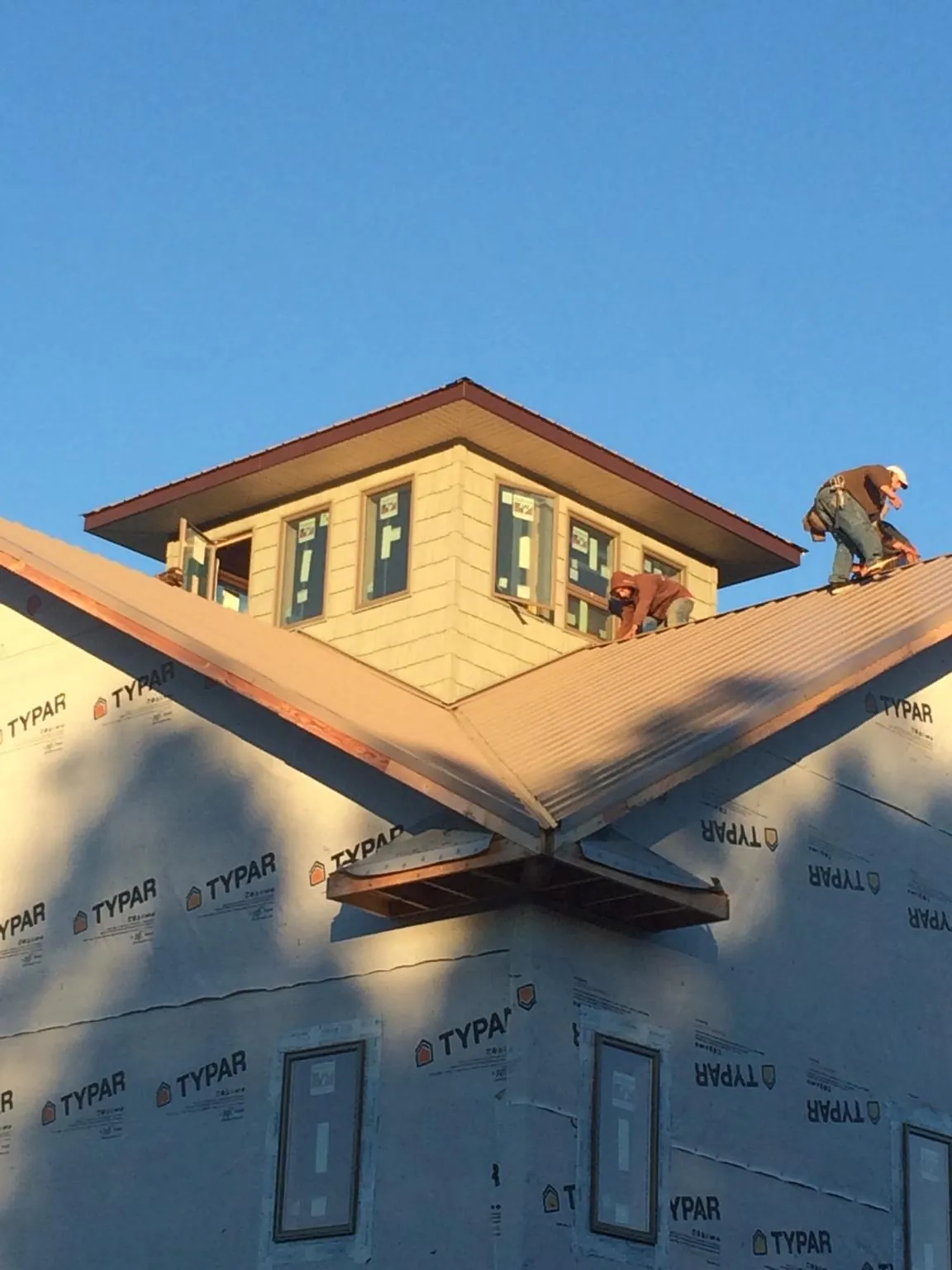 Roofers working around a rooftop cupola on a new metal roof at sunset — Roof Waterproofing in Coldwater by Roofing Brothers